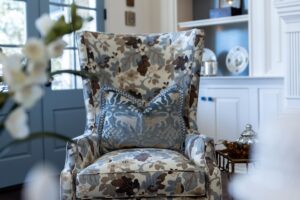 Draped in Style, Louisville’s best for custom drapery, showcases floral armchair with decorative blue pillow, blue door, and white shelves.