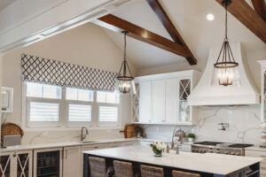 Modern Louisville kitchen with custom draperies, patterned valances, white cabinets, marble countertops, and wicker stools by Draped in Style.
